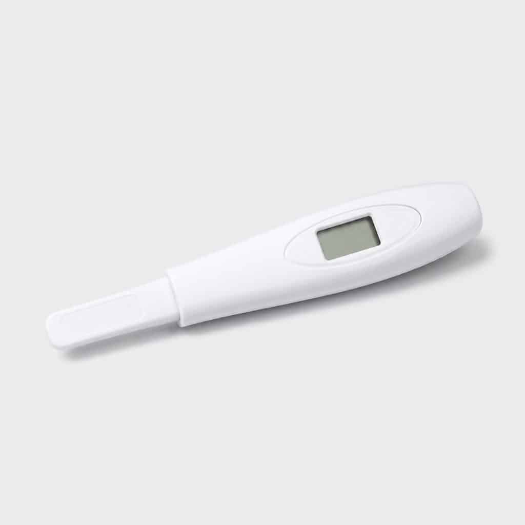 Autotest de grossesse à lecture digitale posé sur fond neutre clair