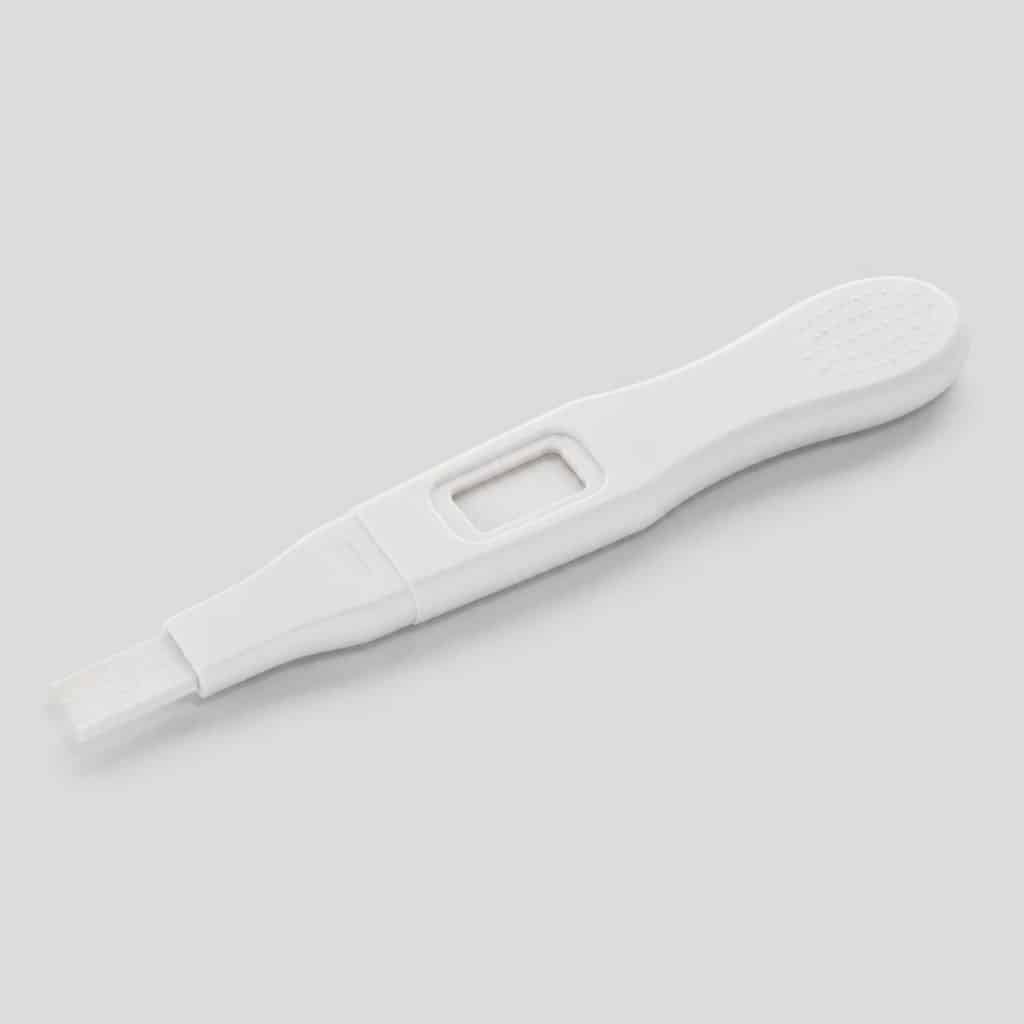 Autotest de grossesse avec résultat en texte clair posé sur fond neutre
