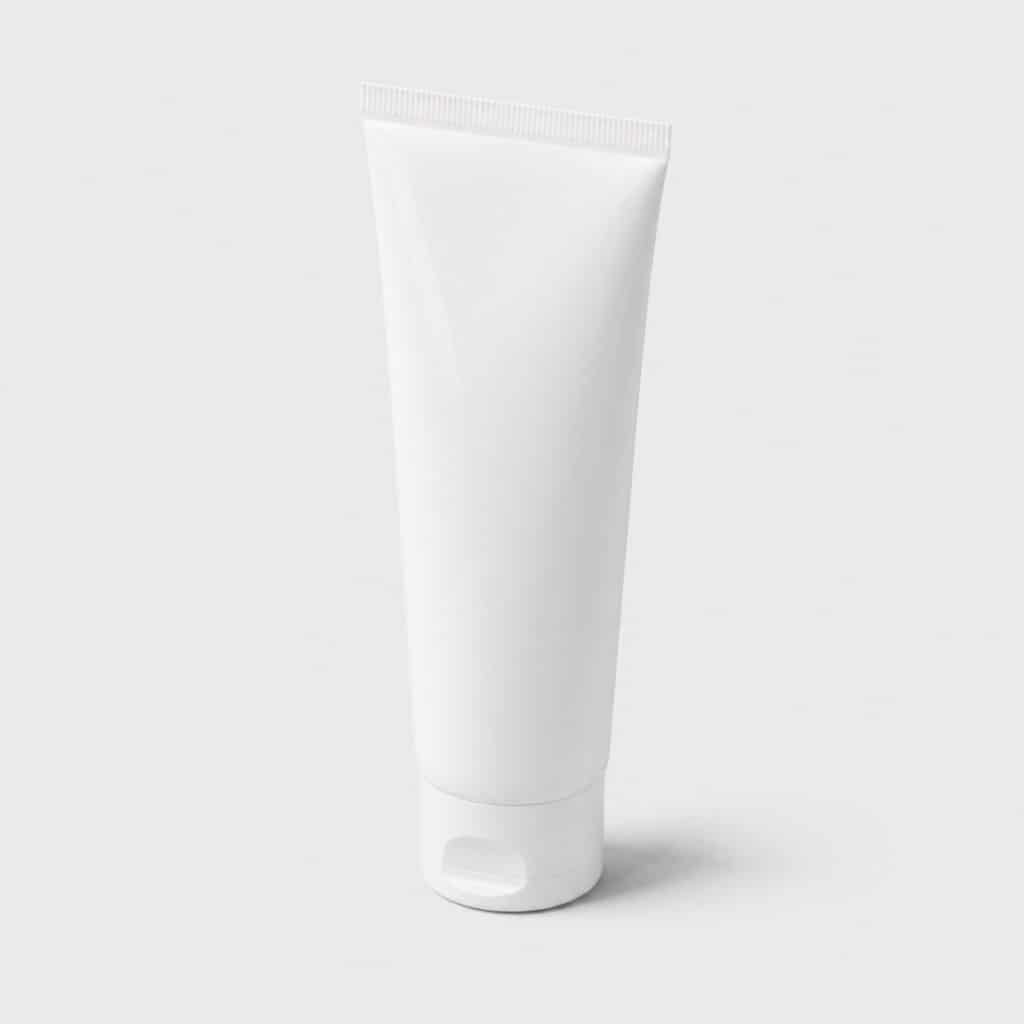 Tube de dentifrice au fluor posé sur fond neutre