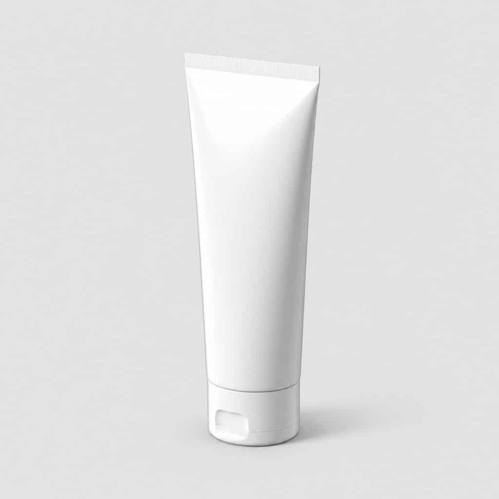 Tube de dentifrice pour gencives sensibles posé sur fond neutre
